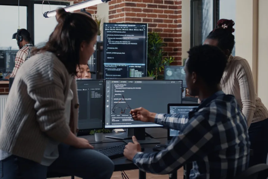 Team collaborating around code dashboards in a modern office